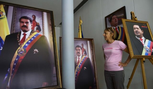 CODEPINK activist Medea Benjamin speaks to reporters, surrounded by pictures of former President of Venezuela Hugo Chavez and current president Nicolas Maduro, near the entrance of the Venezuelan embassy in Washington, DC on April 19, 2019. - Activists opposed to supporters of Venezuelan opposition leader Juan Guaido and their takeover of diplomatic buildings belonging to the Venezuelan government of Nicolas Maduro have been staging a 24/7 vigil to protect the Venezuelan Embassy in Washington DC. (Photo by Andrew CABALLERO-REYNOLDS / AFP)