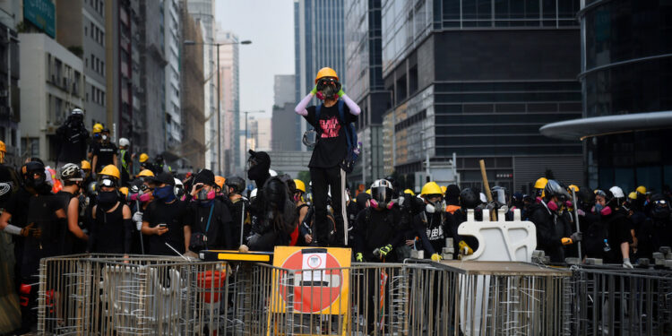 Protesters face off with riot police at Kowloon Bay in Hong Kong on August 24, 2019, in the latest opposition to a planned extradition law that has since morphed into a wider call for democratic rights in the semi-autonomous city. - Hong Kong riot police on August 24 fired tear gas and baton-charged protesters who retaliated with a barrage of stones, bottles and bamboo poles, as a standoff in a working-class district descended into violence. (Photo by Lillian SUWANRUMPHA / AFP)