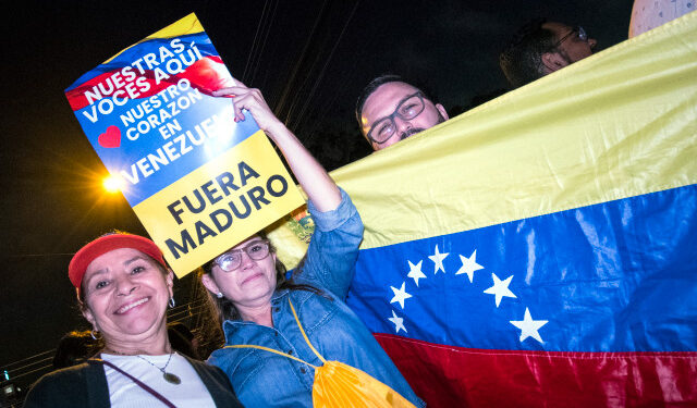 A Venezuelan resident in Costa Rica holds a sign reading "our voices are here, our hearts are in Venezuela, Maduro out" as people gather outside the house of former Costa Rican president and Nobel Peace Prize winner Oscar Arias in San Jose, Costa Rica, January 23, 2019, to thank him for his position against the government of Nicolas Maduro. - The United States and major South American nations recognised Venezuelan opposition leader Juan Guaido as interim leader on January 23 while the EU called for free elections to restore democracy, leaving President Nicolas Maduro increasingly isolated. (Photo by Ezequiel BECERRA / AFP)