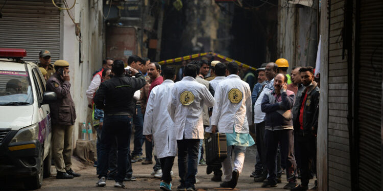 A forensics team walks along a street leading to a factory site where a fire broke out, in Anaj Mandi area of New Delhi on December 8, 2019. - At least 43 people have died in a factory fire in India's capital New Delhi, with the toll expected to rise, police told AFP. The blaze broke out in the early hours in the city's old quarter, whose narrow and congested lanes are lined with many small manufacturing and storage units. (Photo by Sajjad  HUSSAIN / AFP)