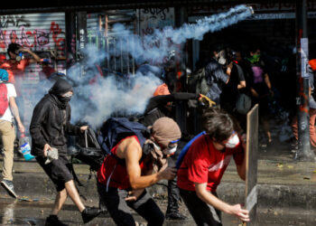 Demonstrators clash with riot police during a protest against the government and to commemorate the first anniversary of the death of Mapuche indigenous leader Camilo Castrillanca -killed in a police operation- in Santiago, on November 14, 2019. - The demonstrators are demanding greater social reform from President Sebastian Pinera, who has announced several measures in a bid to appease protesters, including a pledge to change the constitution that dates from the 1973-90 Augusto Pinochet dictatorship. (Photo by JAVIER TORRES / AFP)