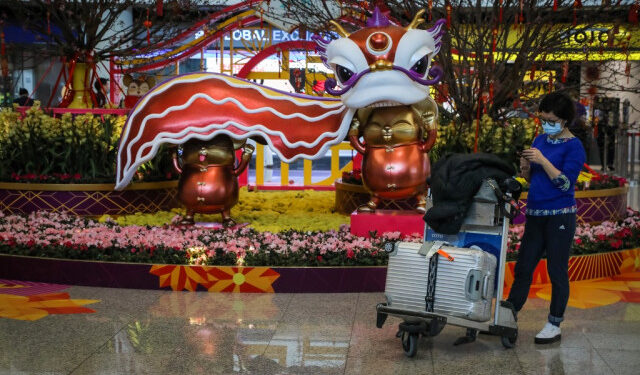 A traveller wearing a face mask as a precautionary measure to protect against the possible spread of a SARS-like virus outbreak stands in the arrivals area at Hong Kong International Airport ahead of the Chinese New Year in Hong Kong on January 23, 2020. - Hong Kong has turned two holiday camps, including a former military barracks, into quarantine zones for people who may have come into contact with carriers of the Wuhan virus, officials announced on January 23. The international financial hub has been on high alert for the virus, which has killed 17 people since the outbreak started in central China. (Photo by VIVEK PRAKASH / AFP)