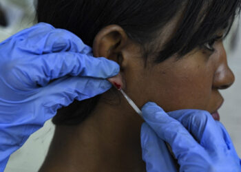 A Venezuelan Health official performs a blood test on a woman at a the Center for Malaria Studies in the Central University of Venezuela in Caracas on April 29, 2019. - In a country with an epidemic of malaria, where according to the pharmaceutical industry 85% of medicines are scarce, patients find respite at the Center for Malaria Studies, that with a very small budget depends on donations. (Photo by YURI CORTEZ / AFP)