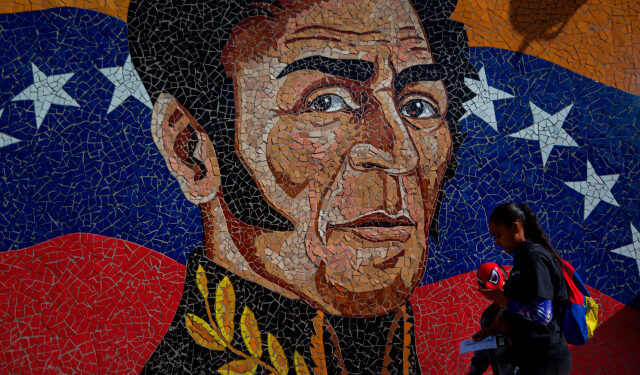 AME7169. CARACAS (VENEZUELA), 25/02/2020.- Fotografía del 11 de febrero del 2020 donde se observa un mural con la imagen del héroe nacional Simón Bolivar mientras una mujer camina con un niño que usa una mascara del hombre araña en Caracas (Venezuela). Simón Bolívar ha renacido cada vez que un líder venezolano necesitaba desempolvar viejas glorias o dar lustre a un gobierno. Su última resurrección fue a lomos de una revolución de aspiración socialista que lo forjó a su imagen y semejanza para devolverlo a las escuelas transformado en su icono. EFE/MIGUEL GUTIERREZ