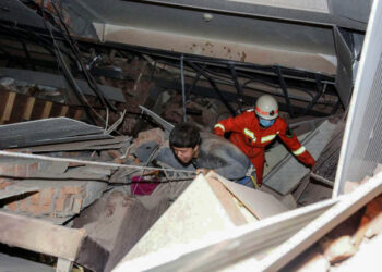 A man (L) is helped by rescuers as he is pulled from the rubble of a collapsed hotel in Quanzhou, in China's eastern Fujian province on March 7, 2020. - Around 70 people were trapped after the Xinjia Hotel collapsed on March 7 evening, officials said. (Photo by STR / AFP) / China OUT