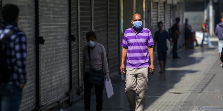 People wear face masks as a precautionary measure against the spread of the new coronavirus, COVID-19, in Caracas, on March 16, 2020. - Venezuelan President Nicolas Maduro ordered on Sunday a "collective quarantine" in seven states, including the capital Caracas, from Monday to stem the spread of the new coronavirus pandemic. (Photo by Cristian Hernandez / AFP)