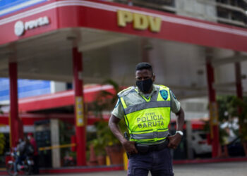 A member of Baruta Municipal Police stands guard near a gas station wearing a face mask as a precautionary measure against the spread of the new coronavirus, COVID-19, in Caracas on March 23, 2020. - Venezuela is facing the novel coronavirus pandemic while suffering a major gasoline shortage and with the country's water system collapsed, which has left many homes without running water. (Photo by Cristian Hernandez / AFP)