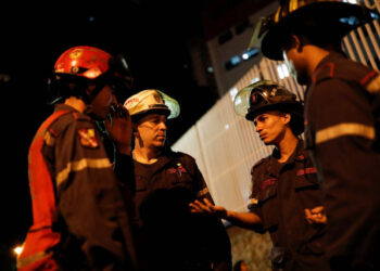 Firefighters talk in the surrounding area of the skyscraper known as the "Tower of David" after an earthquake in Caracas, Venezuela August 21, 2018. REUTERS/Carlos Garcia Rawlins