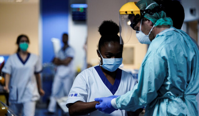 Medical workers put on their protective gears before working on March 27, 2020, at the unit for coronavirus COVID-19 infected patients at the Erasme Hospital in Brussels. (Photo by Kenzo TRIBOUILLARD / AFP)