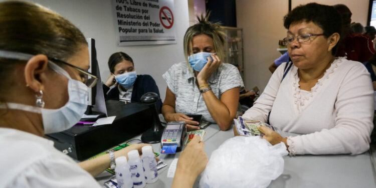 Women buy face masks, alcohol and disinfectant solutions at a pharmacy clerk as Venezuelans rush to buy hand sanitizers and masks in the face of the global COVID-19 coronavirus pandemic, in Caracas, on March 13, 2020. (Photo by CRISTIAN HERNANDEZ / AFP)