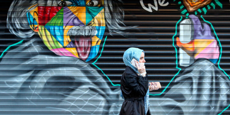 Istanbul (Turkey), 03/04/2020.- A woman wearing a protective face mask walks in front of a street graffiti depicting theoretical physicist Albert Einstein amid the ongoing coronavirus COVID-19 pandemic in Istanbul, Turkey, 03 April 2020. Turkey suspended all international flights and all inter-city travels are subject to local authorities' permission as part of measures to prevent the spread of the pandemic COVID-19 disease caused by the SARS-CoV-2 coronavirus. The country decided also to halt public events, temporarily shut down schools, and suspend sporting events. (Turquía, Estanbul) EFE/EPA/SEDAT SUNA