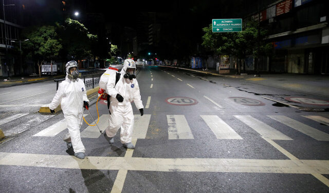 Workers in protective suits walk on the street during the national quarantine in response to the spread of coronavirus disease (COVID-19) in Caracas, Venezuela, March 21, 2020. REUTERS/Manaure Quintero