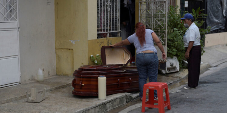 A woman looks into a coffin holding the dead body of her mother after she died at home yesterday, during the outbreak of the coronavirus disease (COVID-19), in Guayaquil, Ecuador March 31, 2020. REUTERS/Vicente Gaibor del Pino NO RESALES. NO ARCHIVES