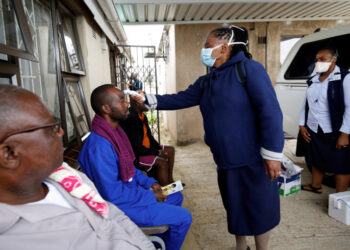 FILE PHOTO: A health worker checks a man's temperature during a door-to-door testing in an attempt to contain the coronavirus disease (COVID-19) outbreak, in Umlazi township near Durban, South Africa, April 4, 2020. REUTERS/Rogan Ward/File Photo