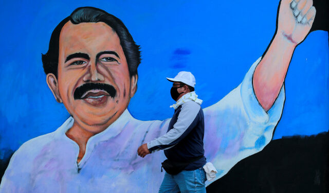 Un hombre con mascarilla para protegerse del coronavirus camina junto a un mural que representa al presidente nicaragüense Daniel Ortega, en Managua, Nicaragua. 30 de marzo de 2020.  REUTERS/Oswaldo Rivas