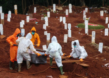 Workers move a coffin of a victim of the COVID-19 coronavirus to a burial site at a cemetery in Jakarta on April 15, 2020. (Photo by BAY ISMOYO / AFP)