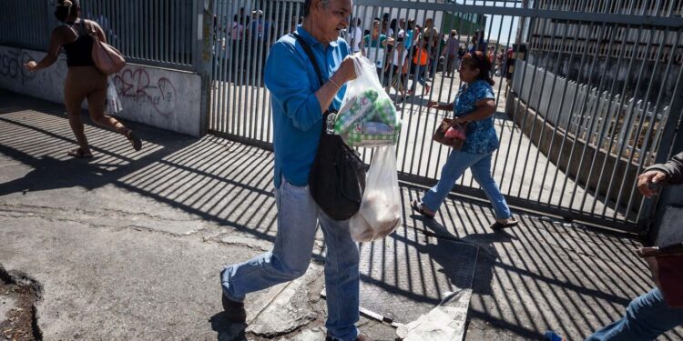 CAR01. CARACAS (VENEZUELA), 16/01/2016.- Un hombre corre luego de comprar arroz en un abasto hoy, sábado 16 de enero de 2016, en la ciudad de Caracas (Venezuela). Venezuela, con las mayores reservas probadas de petróleo del mundo, se declaró en emergencia económica para atender la situación del país que después de un año de opacidad reveló una inflación interanual de 141,5 por ciento -la más alta de toda su historia-, y una contracción del 4,5 por ciento. EFE/MIGUEL GUTIÉRREZ