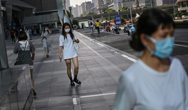 Women wearing a face mask walk in a street of Wuhan, in Chinas central Hubei province on May 18, 2020. - Authorities in the pandemic ground zero city of Wuhan have ordered mass COVID-19 testing for all 11 million residents after a new cluster of cases emerged over the weekend. (Photo by Hector RETAMAL / AFP)