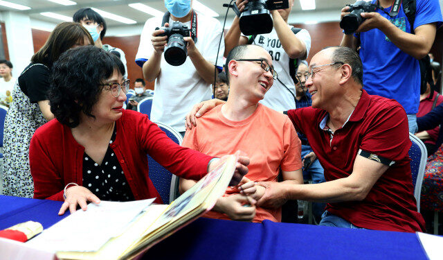 This photo taken on May 18, 2020 shows Mao Yin (C) speaking with his mother Li Jingzhi (L) and father Mao Zhenping (R) in Xian, in China's northern Shaanxi province. - A Chinese man who was kidnapped as a toddler 32 years ago has been reunited with his biological parents, after police used facial recognition technology to track him down. (Photo by STR / AFP) / China OUT