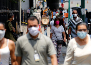 People wearing protective masks walk on a street during a nationwide quarantine as the spread of the coronavirus disease (COVID-19) continues, in Caracas, Venezuela April 20, 2020. REUTERS/Manaure Quintero