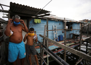 Foto de archivo de un hombre y un niño ajustándose sus máscaras en una barriada pobre en Manaus, Brasil, en medio de la pandemia de coronavirus.
May 19, 2020. REUTERS/Bruno Kelly