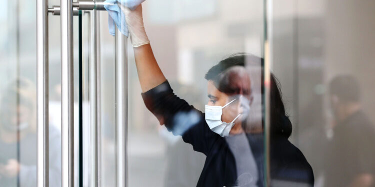 A worker wearing a protective mask sanitizes door handles at an Apple Inc. store reopening, after being closed due to lockdown measures imposed because of the coronavirus, in the Bondi Junction suburb of Sydney, Australia, on Thursday, May 7, 2020. Apple's app store saw its strongest month of growth in two and a half years in April, according to Morgan Stanley, which wrote that "all major regions & categories saw accelerating spend" as a result of the pandemic. Photographer: Brendon Thorne/Bloomberg