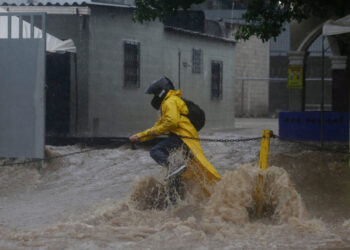 AME3495. SAN SALVADOR (EL SALVADOR), 31/05/2020.- Un persona intenta cruzar una calle inundada debido al paso de la tormenta tropical Amanda en San Salvador (El Salvador). Las intensas lluvias generadas por la tormenta tropical Amanda en El Salvador causaron este domingo la muerte de al menos nueve personas, inundaciones y la destrucción de 50 viviendas en la capital del país centroamericano, informaron las autoridades. EFE/Rodrigo Sura