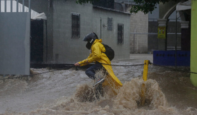 AME3495. SAN SALVADOR (EL SALVADOR), 31/05/2020.- Un persona intenta cruzar una calle inundada debido al paso de la tormenta tropical Amanda en San Salvador (El Salvador). Las intensas lluvias generadas por la tormenta tropical Amanda en El Salvador causaron este domingo la muerte de al menos nueve personas, inundaciones y la destrucción de 50 viviendas en la capital del país centroamericano, informaron las autoridades. EFE/Rodrigo Sura