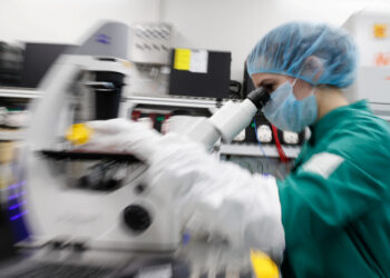 A scientist examines COVID-19 infected cells under a microscope during research for a vaccine against the coronavirus disease (COVID-19) at a laboratory of BIOCAD biotechnology company in Saint Petersburg, Russia May 20, 2020. REUTERS/Anton Vaganov