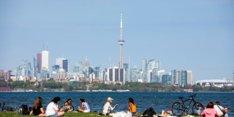 FILE PHOTO: People maintain social distance as they sit at Humber Bay Shores park while the province prepares for more phased re-openings from the coronavirus disease (COVID-19) restrictions in Toronto, Ontario, Canada May 24, 2020. REUTERS/Carlos Osorio/File Photo