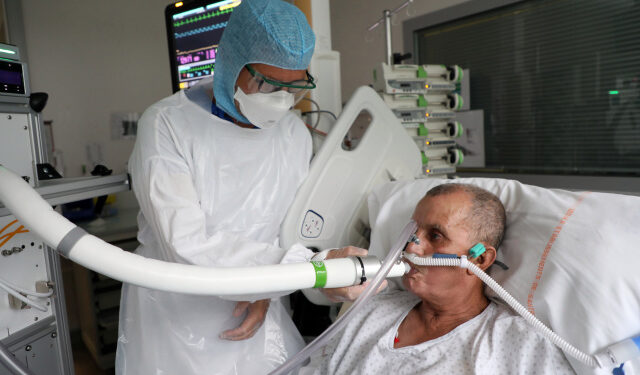 Christian George, director de investigación del Centro Nacional de Investigación Científica, ayuda a un paciente que sufre de COVID-19, la enfermedad causada por el coronavirus, a usar la máquina que examina el aliento en el Hospital La Croix-Rousse en Lyon, Francia. 22 de julio, 2020. REUTERS/Yiming Woo