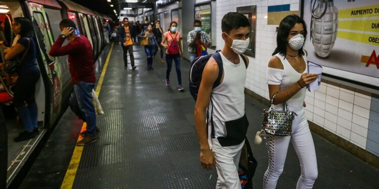 People travel on the subway wearing protective masks as a preventive measure in the face of the global COVID-19 coronavirus pandemic, in Caracas, on March 14, 2020. - Venezuela requires a 'mandatory quarantine' for all travelers from Europe who arrived in the country in March, one day after confirming their first two cases of coronavirus. (Photo by Cristian Hernandez / AFP)