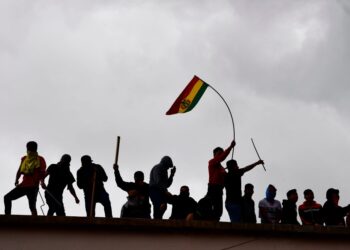 Prisoners flutter Bolivian national flags as they remain on the roof of the San Pedro prison during a riot demanding the resignation of prisons' director Ernesto Vergara in La Paz on November 12, 2019. - Bolivia's Evo Morales was en route to exile in Mexico on Tuesday, leaving behind a country in turmoil after his abrupt resignation as president. The senator set to succeed Morales as interim president, Jeanine Anez, pledged to call fresh elections to end the political crisis. (Photo by RONALDO SCHEMIDT / AFP) (Photo by RONALDO SCHEMIDT/AFP via Getty Images)