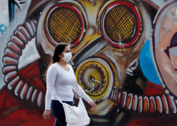 Una mujer con tapabocas camina el pasado jueves 2 de julio del 2020 frente a un grafiti en Bogotá (Colombia). EFE/ Mauricio Dueñas Castañeda