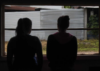 Venezuelan sex workers Joli (L), 35, and her niece Milagro, 19, look through a window during an interview with AFP at a bar in Calamar municipality, Guaviare department, Colombia on October 11, 2018. - Venezuelan migrants who fled their country due to the crisis, turn to prostitution in Colombia for the lack of opportunities to work in other trades. (Photo by Raul ARBOLEDA / AFP)