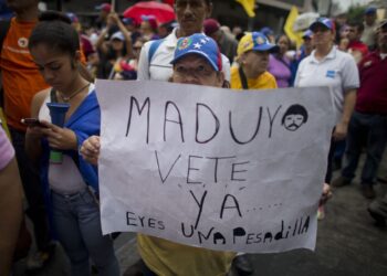 A woman holds a sign with a message that reads in Spanish: "Maduro leave already......you are a nightmare!" during an opposition march in Caracas, Venezuela, Saturday, May 14, 2016. The protesters are demanding that electoral officials accelerate the certification of the petition signatures that would kick off a recall of President Nicolas Maduro. (AP Photo/Ariana Cubillos)