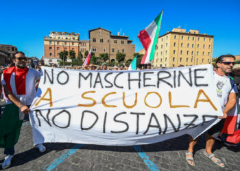 Protesters from "No Mask" movements, Covid deniers movements, anti-5G movements and anti-vaccination movements protest against the government's health policy on September 5, 2020 in Rome during the COVID-19 infection, caused by the novel coronavirus. - The banner reads "No mask at school, no distancing". (Photo by Vincenzo PINTO / AFP)