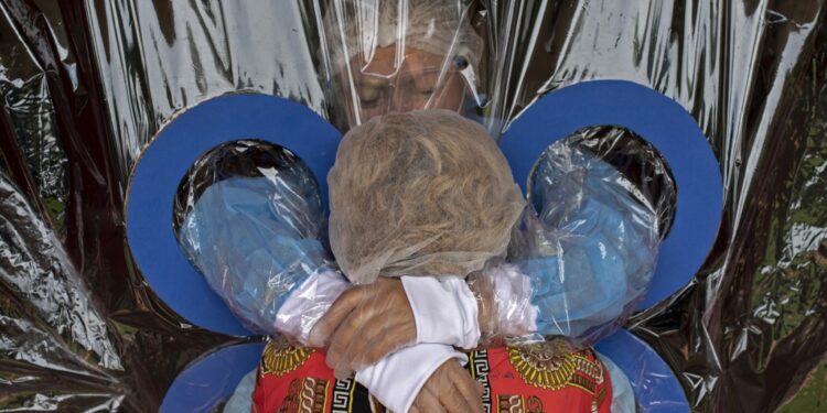 Maria Hernandez, 38, (top) embraces her aunt through a transparent curtain at a Hogar Jardin de Los Abuelitos nursing home in San Salvador on September 11, 2020, amid the new coronavirus pandemic. - According to geriatrician Luis Bermudes, the use of a kind of curtain that allows the elderly guests to be hugged by their relatives without the risk of being infected from COVID-19 is a measure to avoid depression and anxiety. (Photo by Yuri CORTEZ / AFP)