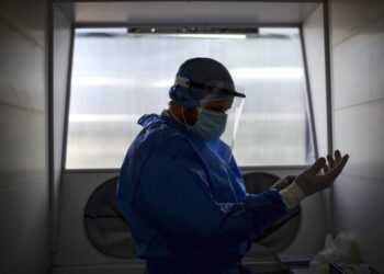 A doctor gets ready to take a swab sample through a protection system at the Professor Alejandro Posadas National Hospital in the municipality of El Palomar, province of Buenos Aires, on September 18, 2020, amid the COVID-19 novel coronavirus pandemic. - The pandemic has killed at least 946,727 people worldwide, including more than 12,000 in Argentina, since emerging in China late last year, according to an AFP tally at 1100 GMT Friday based on official sources. (Photo by Ronaldo SCHEMIDT / AFP)