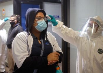 Workers of a truck part factory get their temperature checked as they prepare to resume activities after it was closed for several weeks to prevent the spread of coronavirus in San Luis Potosi, Mexico on May 27, 2020. (Photo by MAURICIO PALOS / AFP)