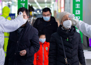 This photo taken on February 18, 2020 shows passengers having their temperature taken as a preventive measure against the COVID-19 coronavirus at a train station in Nanjing, in China's eastern Jiangsu province. - The death toll from China's new coronavirus epidemic jumped past 2,000 on February 19 after 136 more people died, with the number of new cases falling for a second straight day, according to the National Health Commission. (Photo by STR / AFP) / China OUT