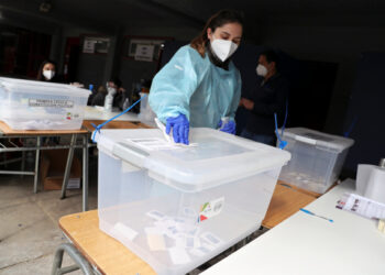 A woman wearing a protective face mask and a suit disinfects a ballot box during a referendum on a new Chilean constitution in Santiago, Chile, October 25, 2020. REUTERS/Ivan Alvarado