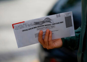 A woman holds a vote-by-mail ballot outside Miami Beach City Hall in Miami Beach, Florida on October 19, 2020. - President Donald Trump lashed out at "stupid" critics from within his own party and called for unity on Sunday after growing Republican criticism and warnings of a "bloodbath" in the November 3 election. Trump issued the comments as he and his Democratic opponent Joe Biden hit the ground in crucial swing states in the final stretch before an election that opinion polls show the real estate mogul is at serious risk of losing. (Photo by Eva Marie UZCATEGUI / AFP) (Photo by EVA MARIE UZCATEGUI/AFP via Getty Images)