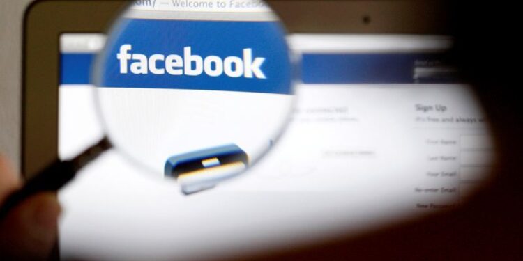 Imagen de archivo ilustrativa del logo de Facebook en una pantalla de computador visto a través de una lupa sostenida por una mujer en Berna, Suiza. 19 de mayo, 2012. REUTERS/Thomas Hodel/Archivo