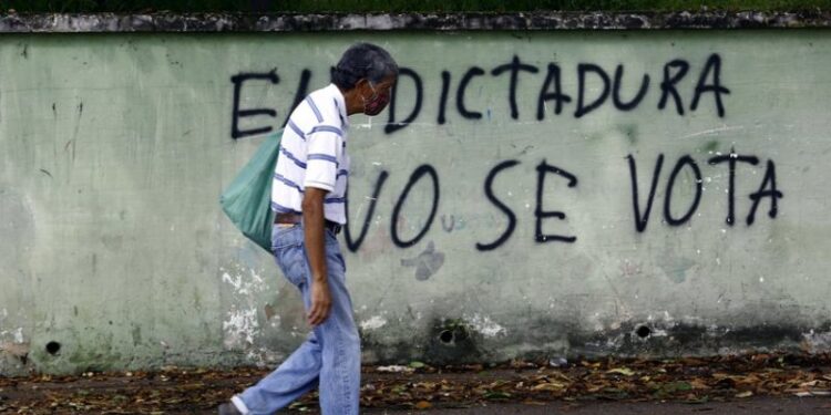 Un hombre pasea junto a un mural contra las elecciones parlamentarias de Venezuela. Zuma Press