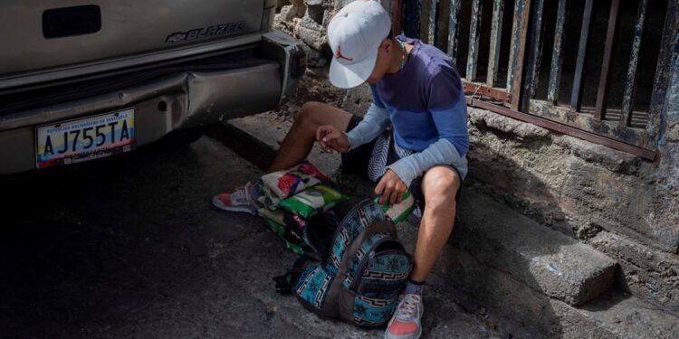 Samuel Antonio, de 24 años, organiza los kilos de arroz que recibió a cambio de plátanos en Catia, el 18 de enero de 2021 en Caracas (Venezuela). Como si de un deporte extremo se tratase, Bryan, Samuel y Alexandra caminan las empinadas calles del barrio caraqueño de Catia con una cesta a cuestas cargada con plátanos. El objetivo: intercambiarlos por productos que luego venderán para poder sobrevivir en medio de la severa crisis económica venezolana. El trueque del siglo XXI. EFE/RAYNER PEÑA R