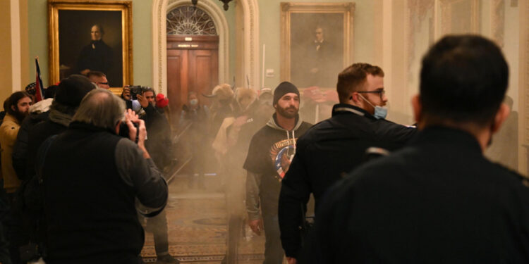 Supporters of US President Donald Trump enter the US Capitol as smoke fills the corridor on January 6, 2021, in Washington, DC. There are no reports of tear gas being used at the Capitol. - Demonstrators breeched security and entered the Capitol as Congress debated the a 2020 presidential election Electoral Vote Certification. (Photo by Saul LOEB / AFP) (Photo by SAUL LOEB/AFP via Getty Images)