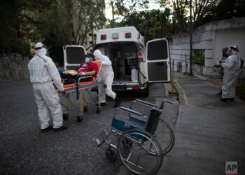 Angels of the Road volunteer paramedics transfer a person suspected of having COVID-19 into their one ambulance, in Caracas, Venezuela, Thursday, Feb. 11, 2021. Each day brings on average three to four calls, and the new coronavirus pandemic means that at least one of those is a request to take a patient with trouble breathing to a hospital. (AP Photo/Ariana Cubillos)