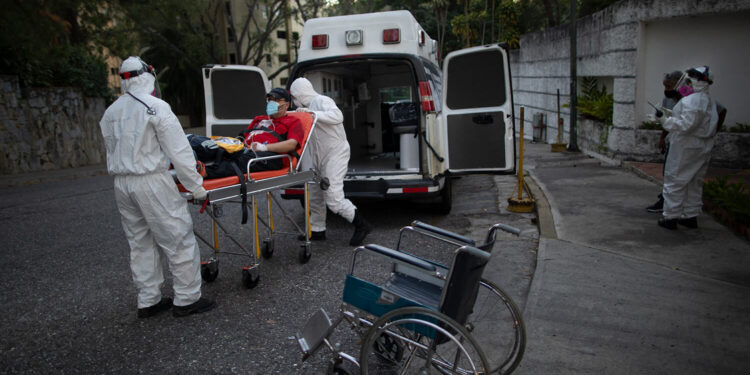 Angels of the Road volunteer paramedics transfer a person suspected of having COVID-19 into their one ambulance, in Caracas, Venezuela, Thursday, Feb. 11, 2021. Each day brings on average three to four calls, and the new coronavirus pandemic means that at least one of those is a request to take a patient with trouble breathing to a hospital. (AP Photo/Ariana Cubillos)