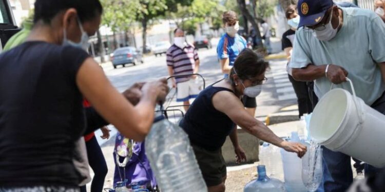 Imagen referencial de personas recolectando agua en una calle, en Caracas, Venezuela. 23 de marzo de 2020. REUTERS. Manaure Quintero